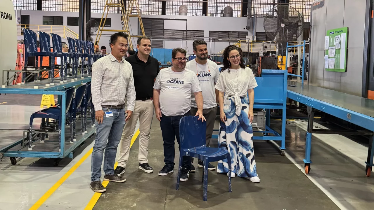 Grupo de pessoas com a cadeira Marina na cor azul na fábrica da Tramontina.