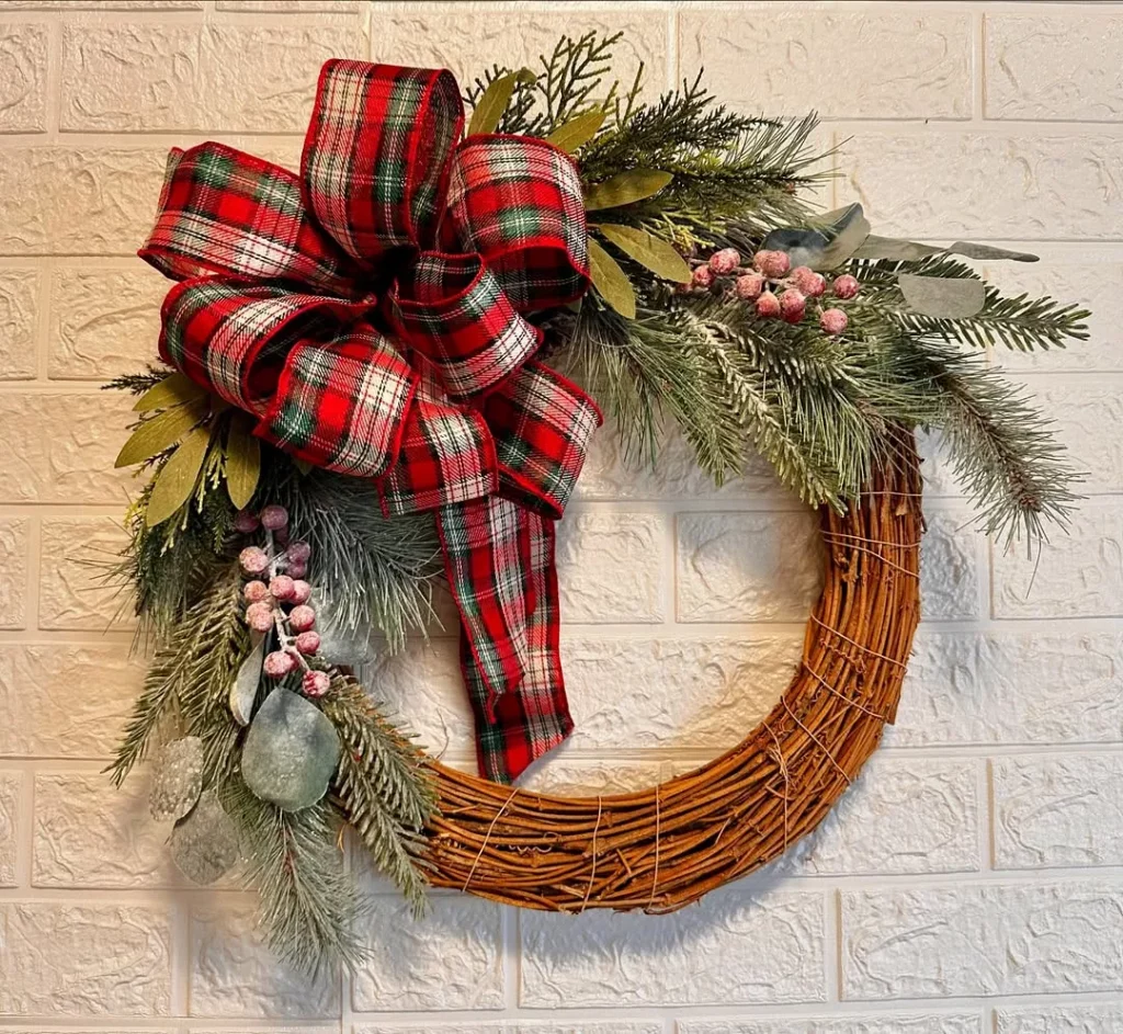 Guirlanda de natal com laço vermelho xadrez, ramos de pinheiro e círculo de galhos de madeira.