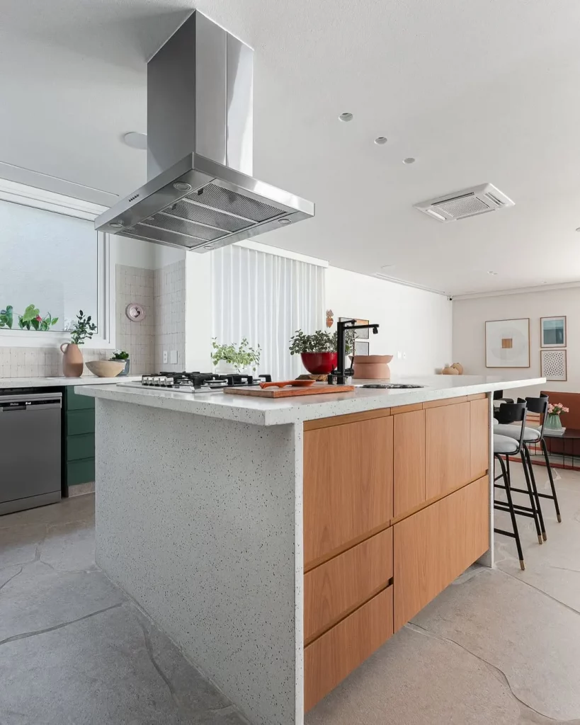 Cozinha com ilha branca e madeira ao lado, compartilhada com sala.