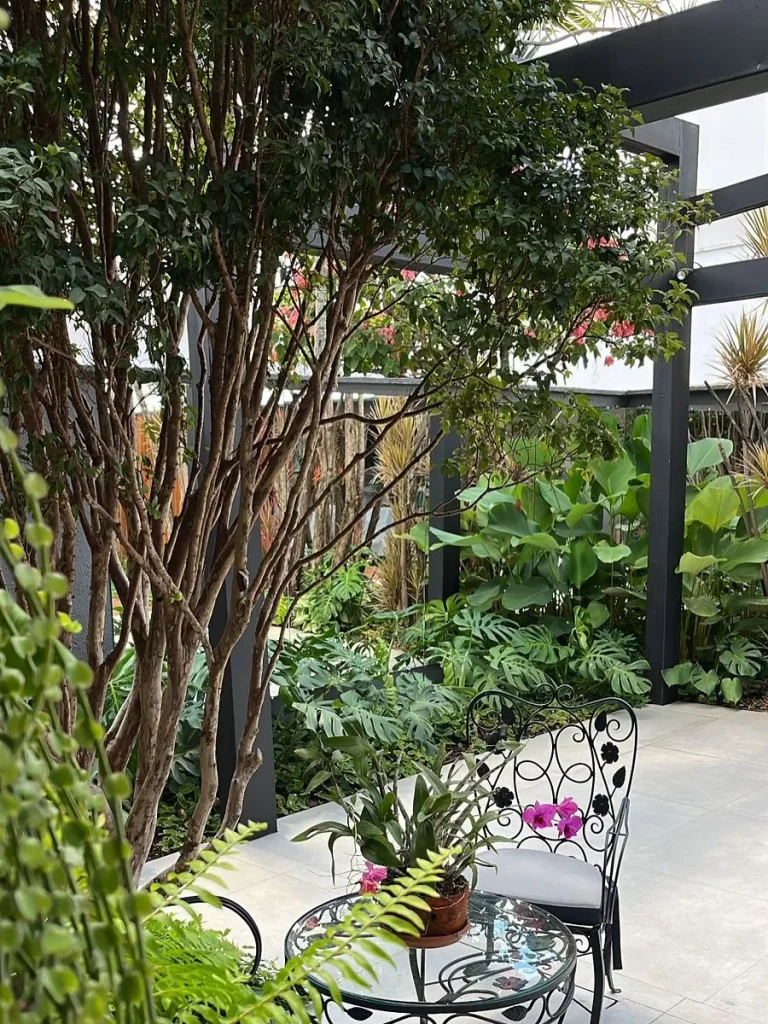 Jardim com cadeira de ferro e piso porcelanato acetinado delicado e cinza claro.