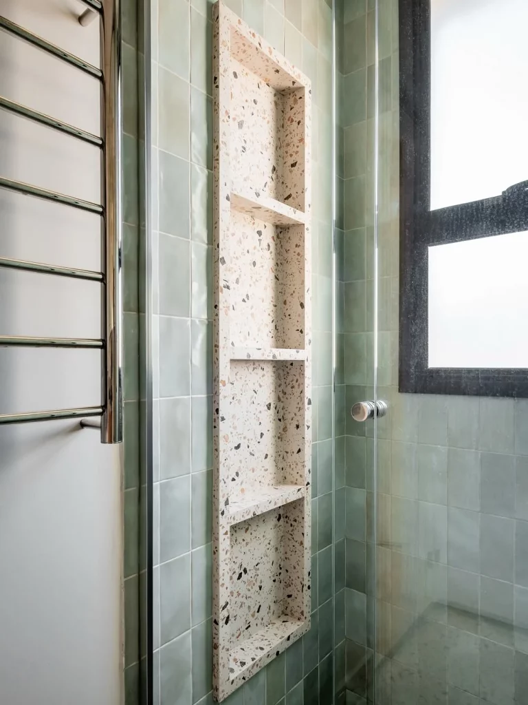 Revestimento verde água no banheiro com nicho de estampa de pedrinhas.