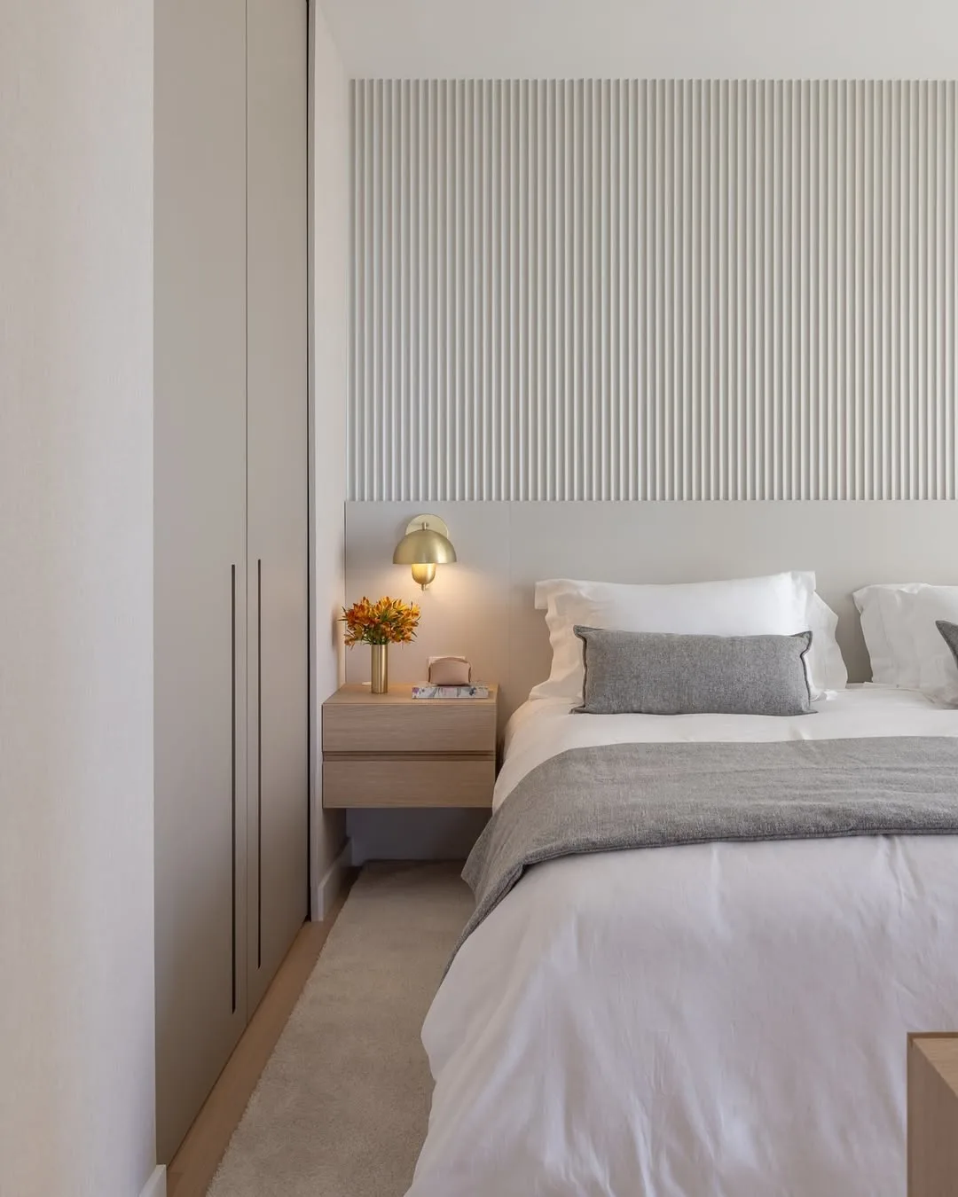 Quarto minimalista cinza com parede texturizada ripada.