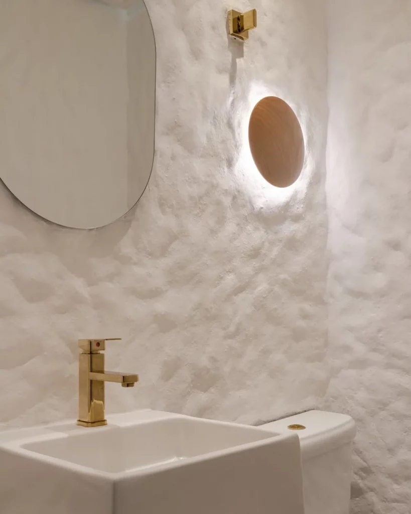 Banheiro com textura na parede e arandela.