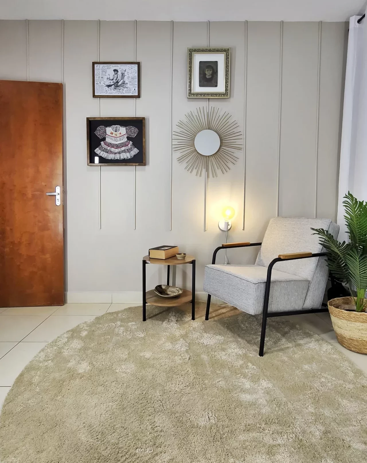 Sala com canaletas, poltrona cinza, mesa lateral e decoração afetiva na parede.