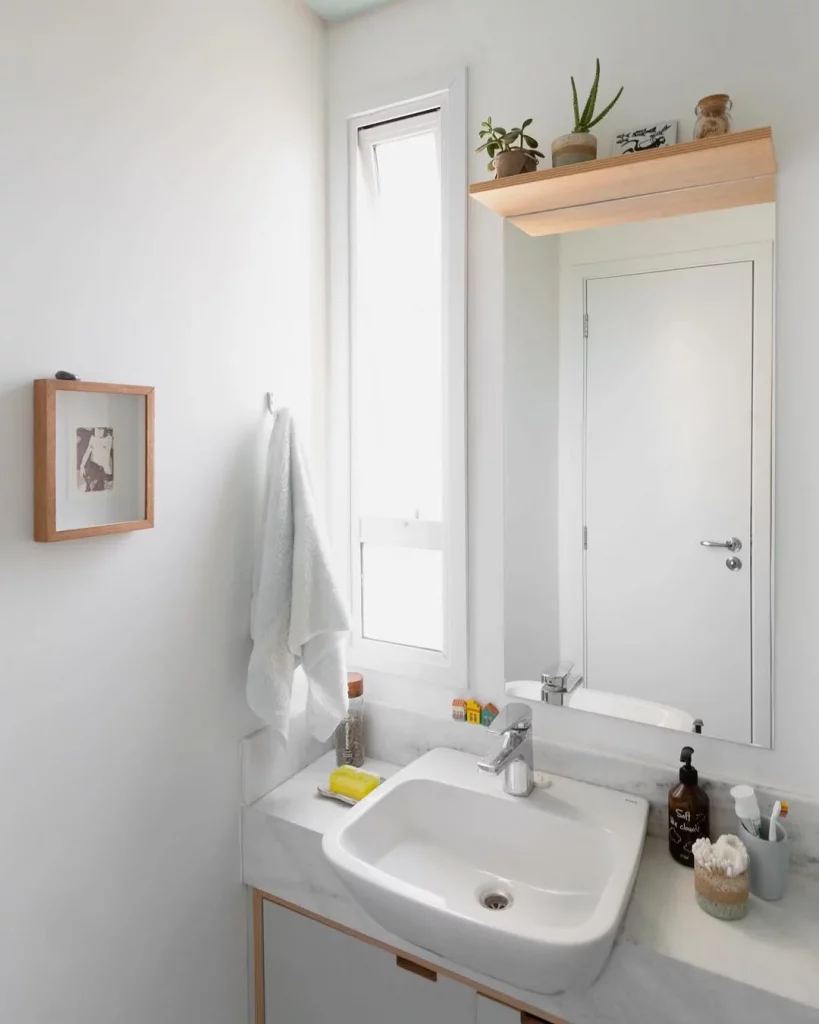 Prateleira de madeira em cima do espelho do banheiro.