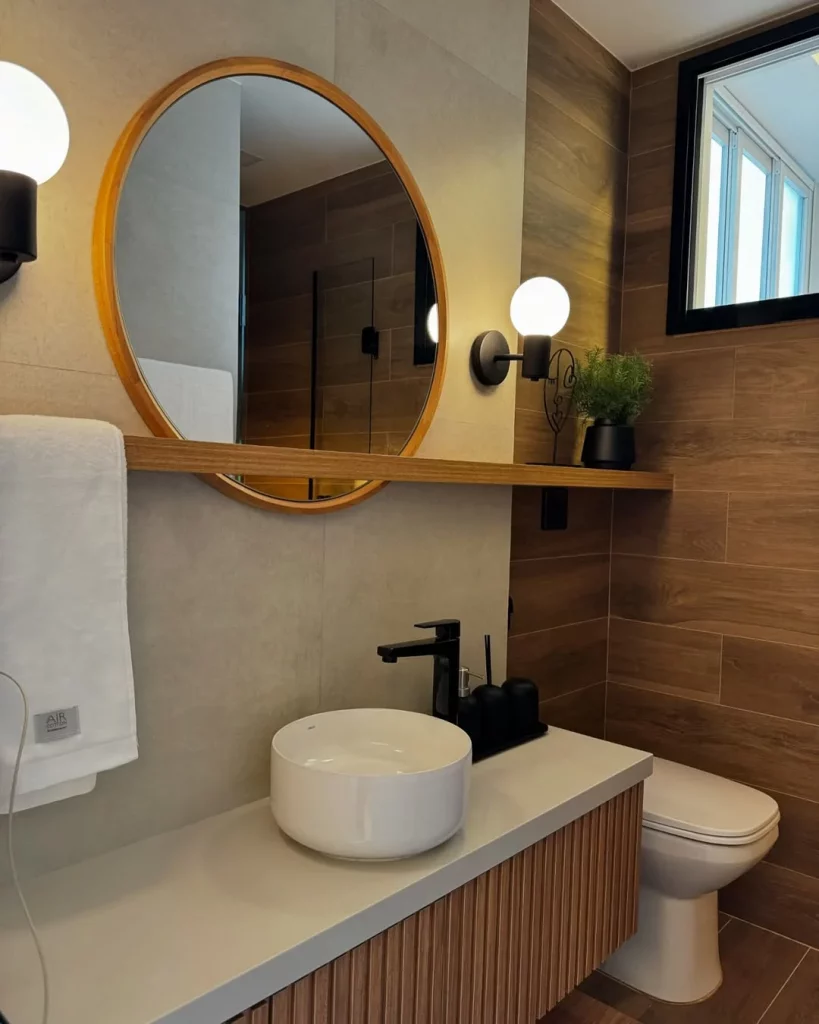 Prateleira perto do espelho de madeira e com toalha pendurada.