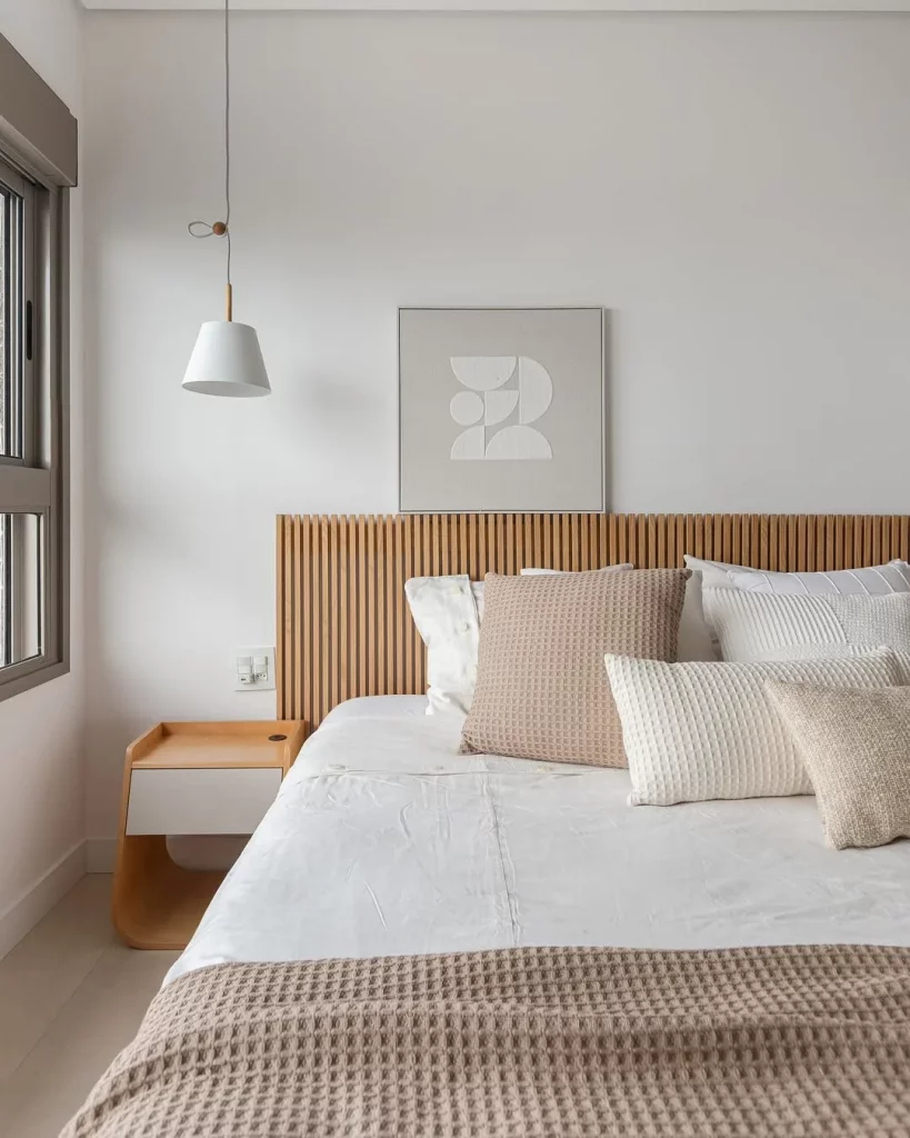 Cabeceira de painel ripado no quarto minimalista com quadro claro.