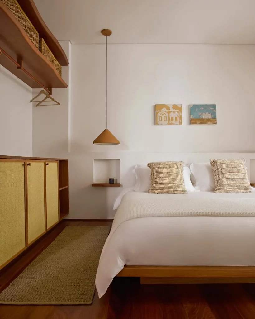 Quarto minimalista com quadros levemente coloridos na parede.