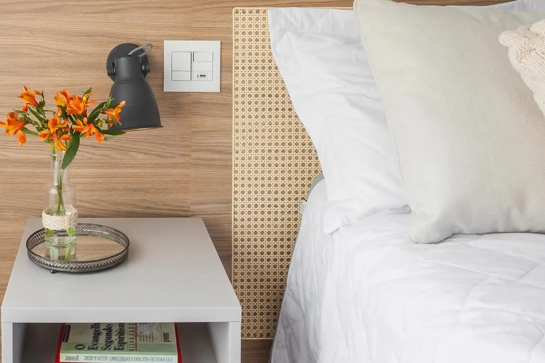 Quarto minimalista com flor delicada e discreta laranja.