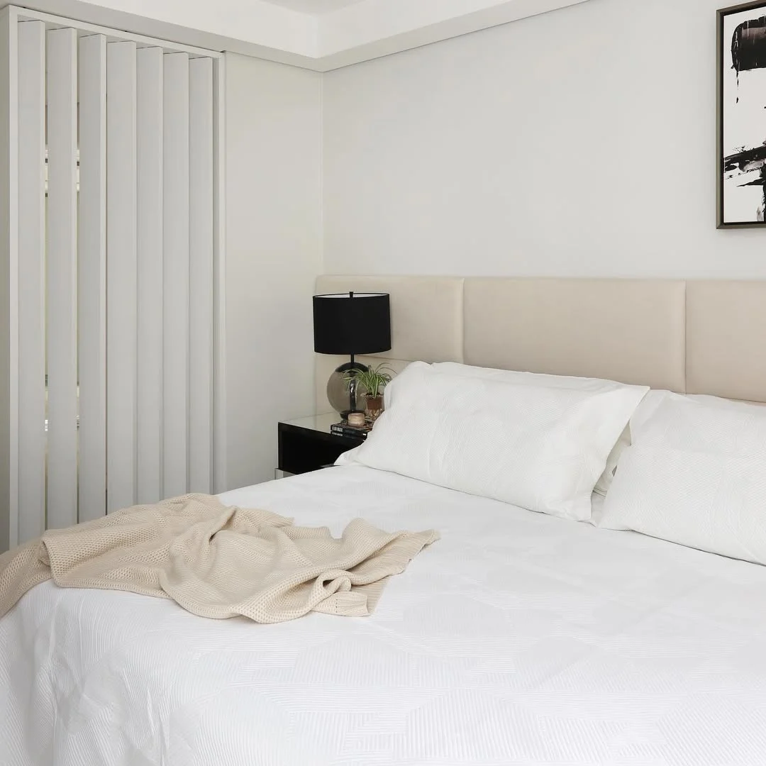 Paleta de cor neutra no quarto minimalista com abajur preto em destaque.
