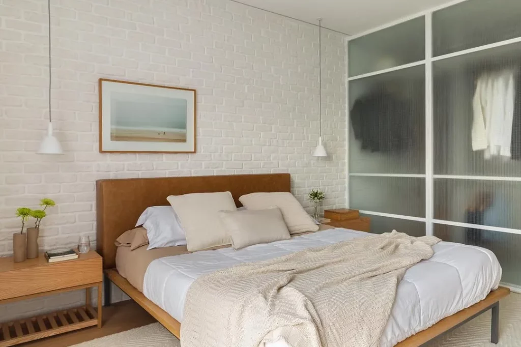 Quarto minimalista com quadro e cabeceira de couro.