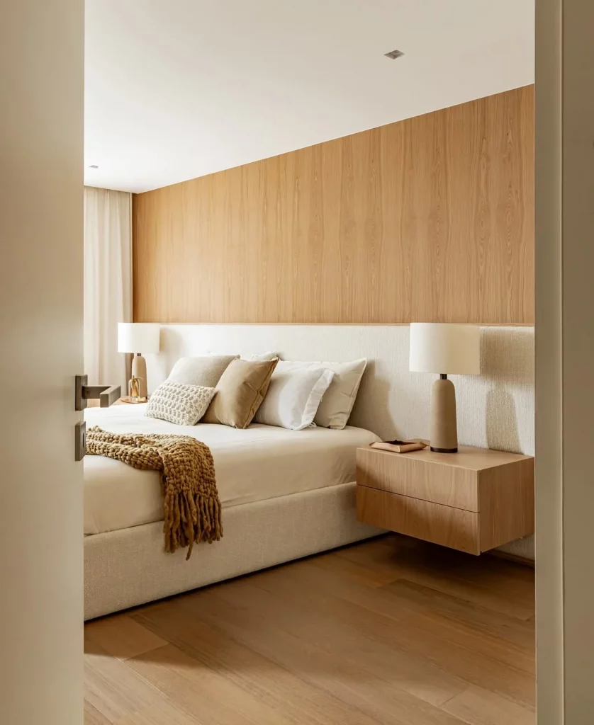 Painel de madeira e cabeceira branca na cama em quarto minimalista.