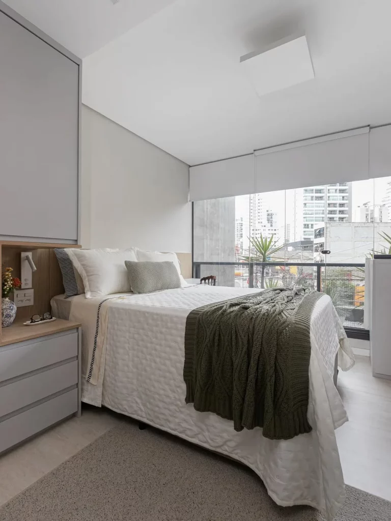 Quarto com parede de vidro e manta de tricô para trazer aconchego.
