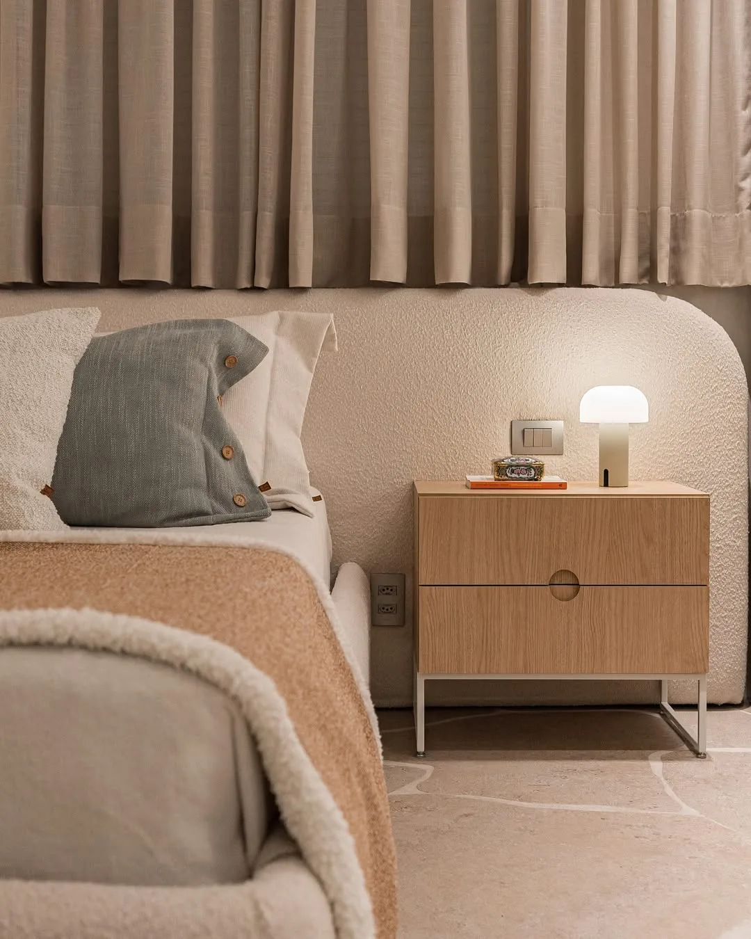 Quarto minimalista com texturas na cama, cabeceira e cortina.