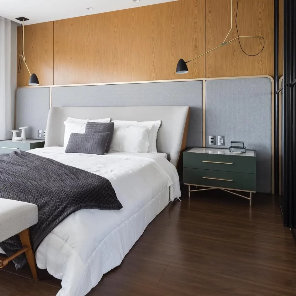 Cabeceira de cama estofada, com painel estofado cinza e madeira na parede.