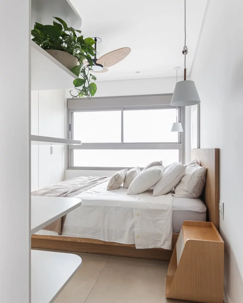 Quarto minimalista branco, com planta na prateleira e piso acetinado.