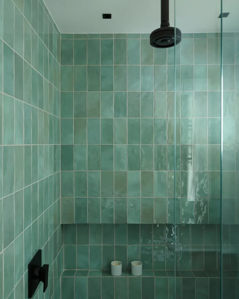Box do banheiro com elementos pretos e revestimento verde água.