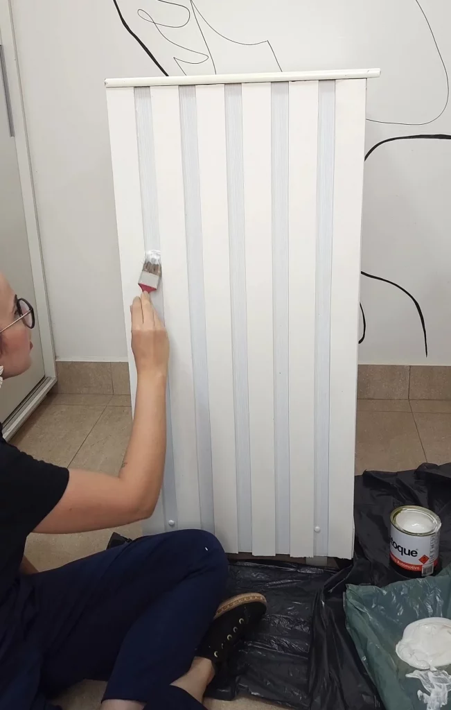 Pintando o rodapé de EVA que imita um painel ripado com pincel.