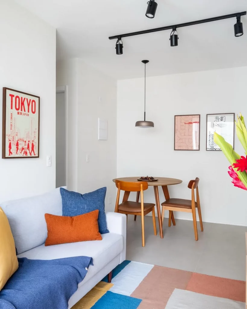 Sala de estar aconchegante com tapete chamativo, almofadas coloridas e quadros na parede.