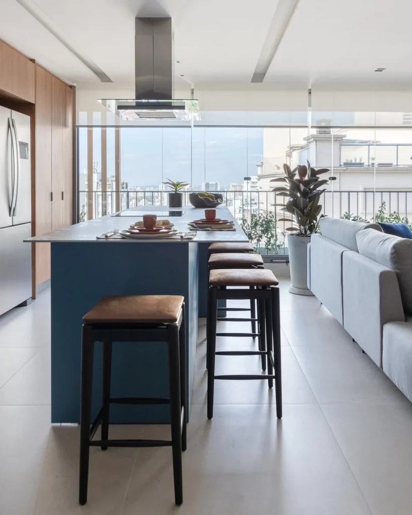 Cozinha e sala conjugada com janela grande de vidro e muita iluminação natural.