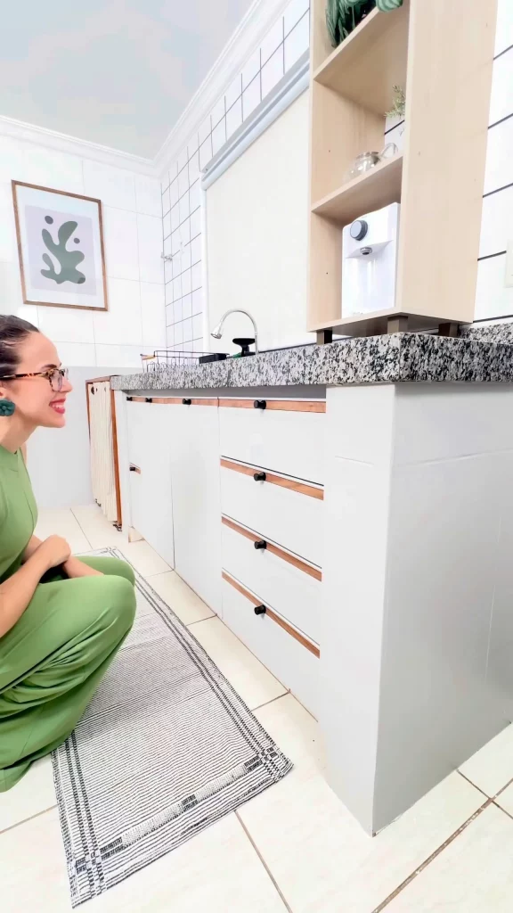 Armário de cozinha envelopado com quadro no fundo, detalhes em madeira e puxador preto.