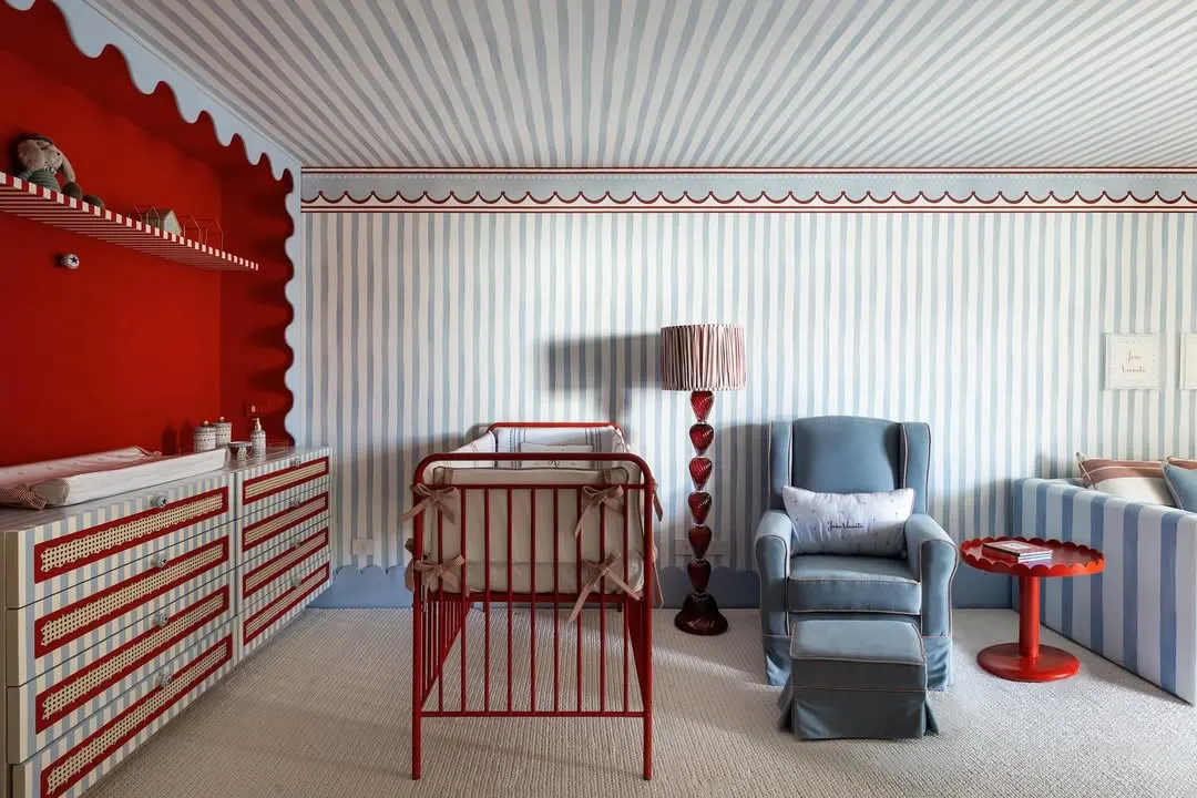 Quarto de bebê com detalhes em azul e vermelho predominantes.