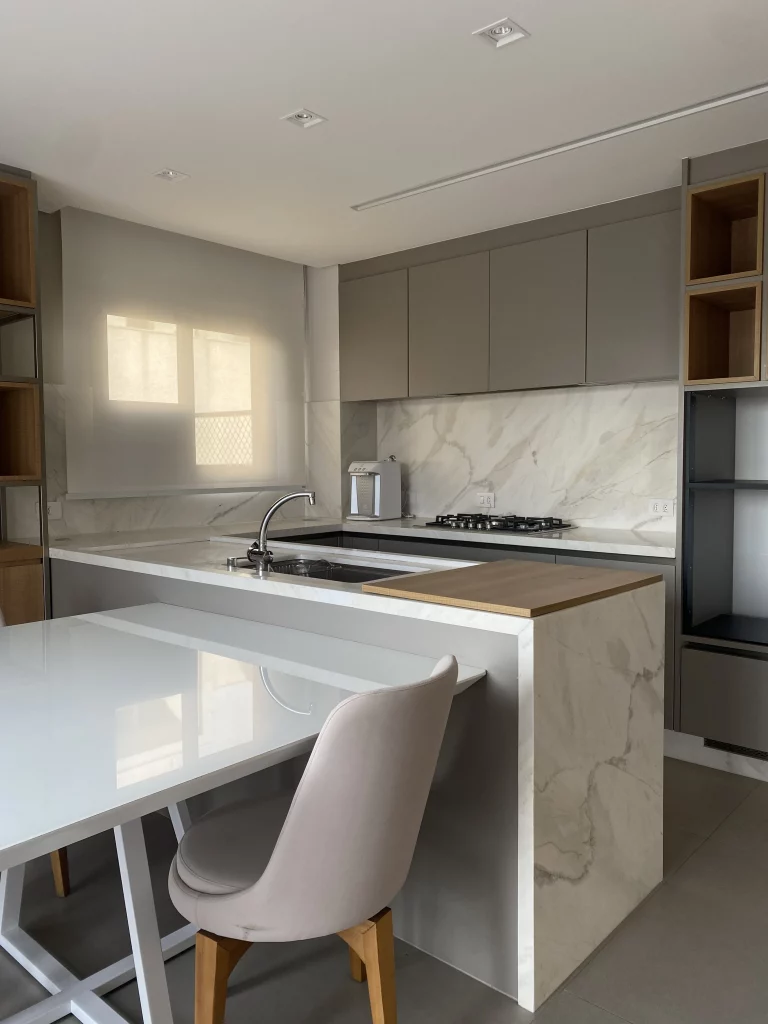 Bancada de cozinha de mármore com tábua de madeira em cima.