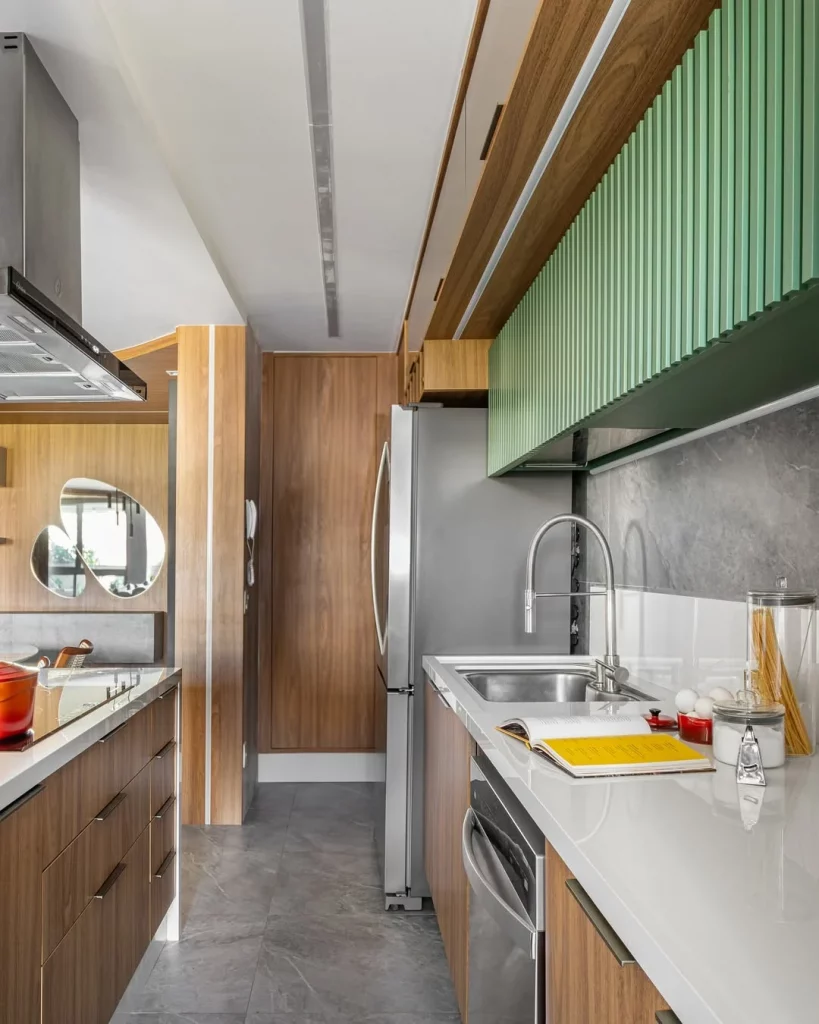 Bancada de cozinha grande e com armário verde em cima.