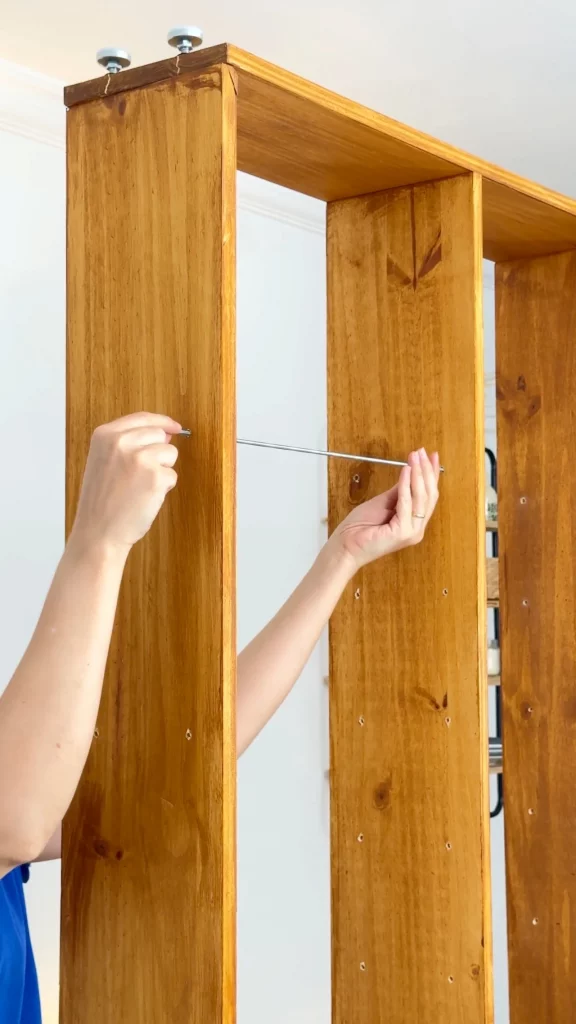 Passando as barras roscadas pelos furos nas tábuas.
