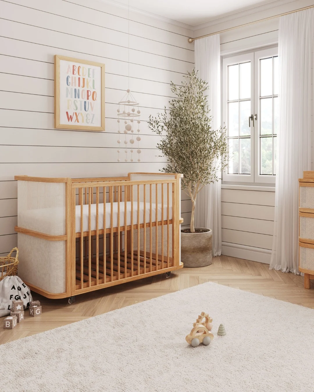 Berço de quarto de bebê de madeira, parede listrada e tapete branco.