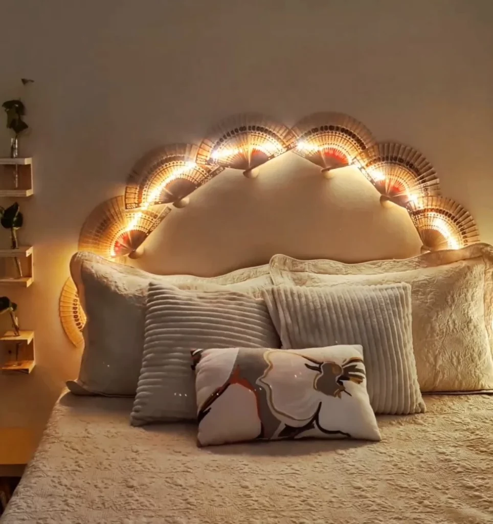 Cabeceira iluminada com leques em formato de arco, almofadas na cama.