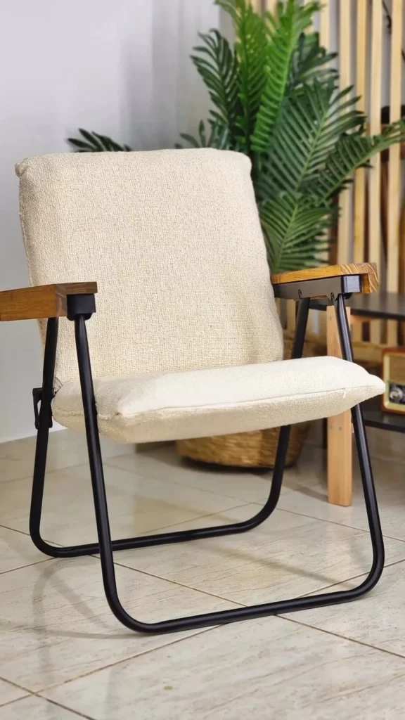 Cadeira de praia transformada em poltrona branca, com metal preto e braço de madeira.