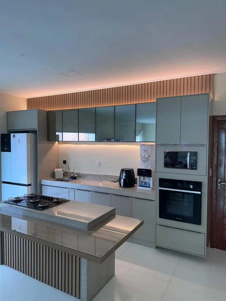 Cozinha com luzes e painel ripado, armário verde e bancada combinando com armários.
