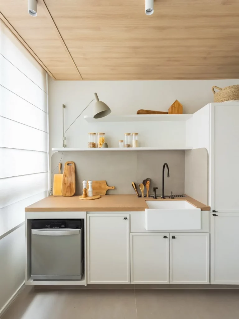 Cozinha com bancada de madeira e pequena, armários brancos.