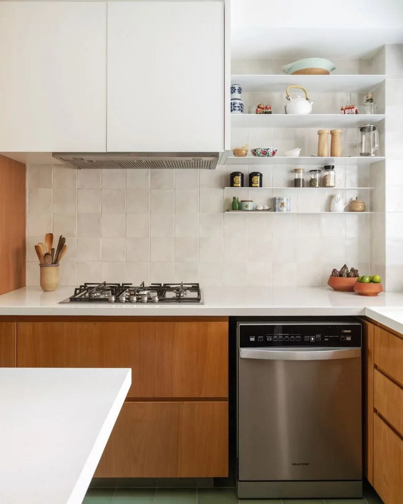 Cozinha com armário de madeira e bancada branca, armário e prateleira na parede.