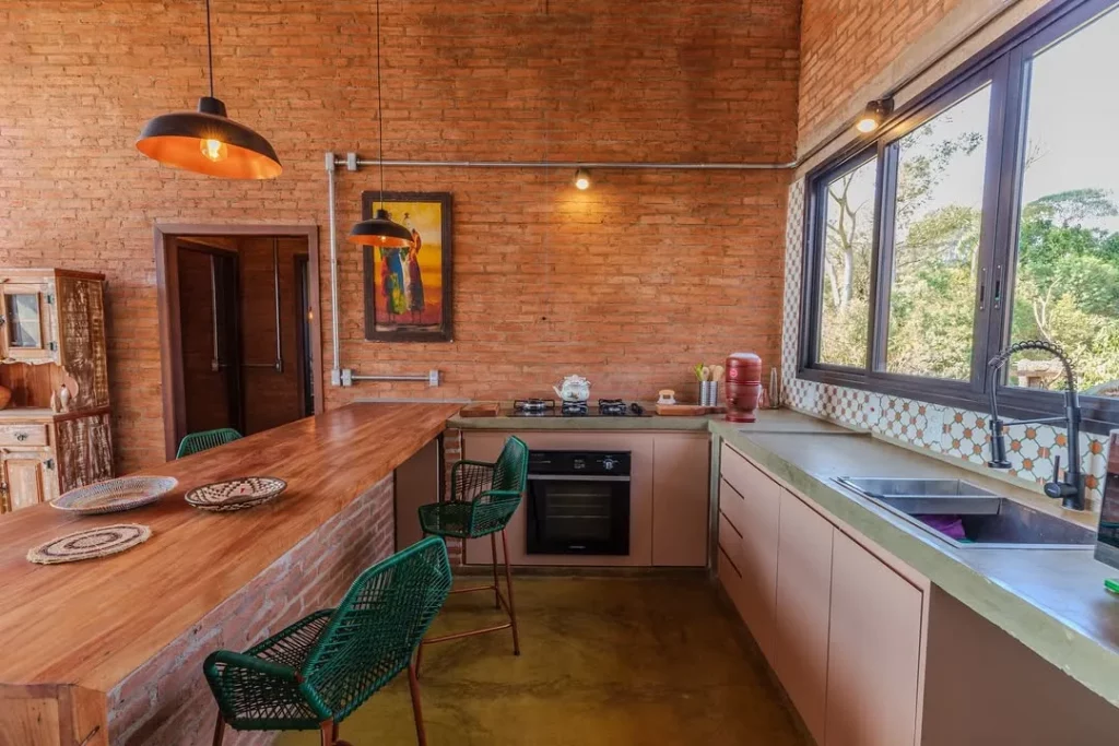 Cozinha com paredes de tijolinhos e armários de madeira.