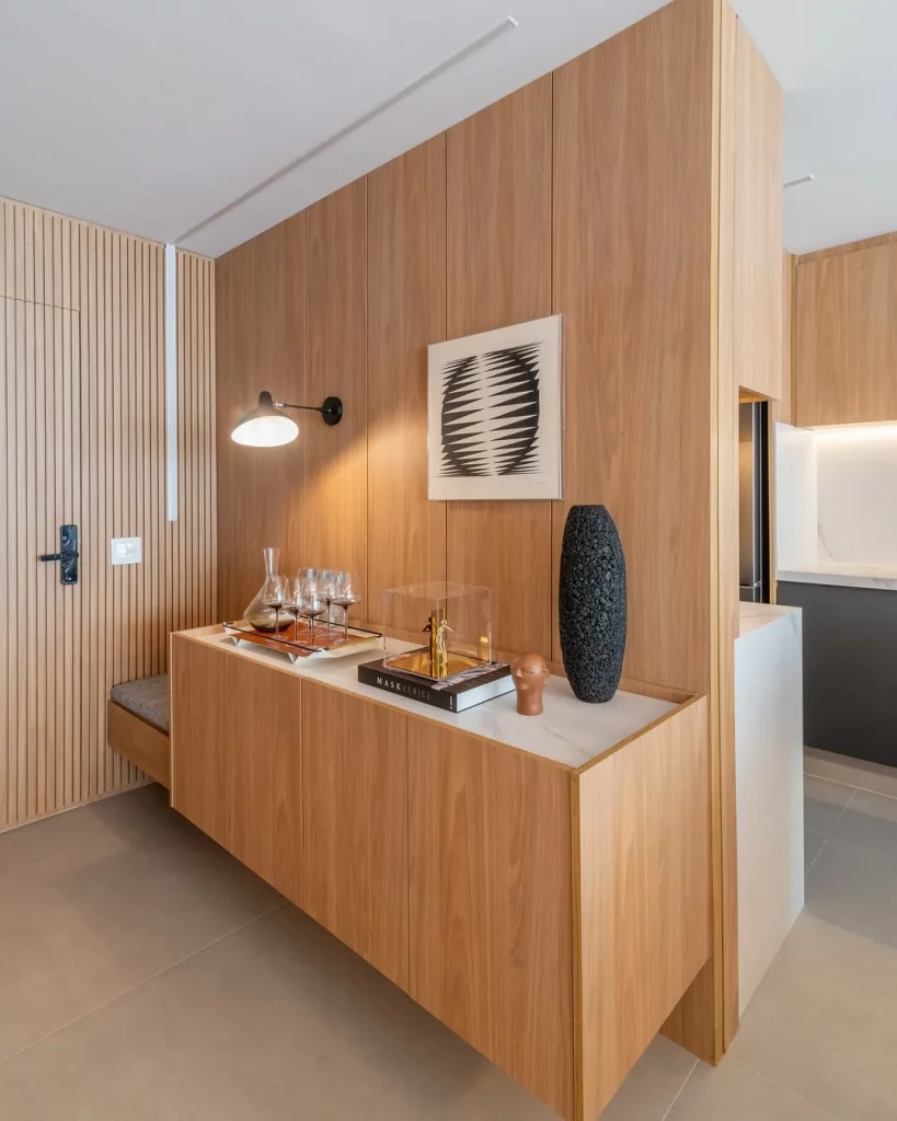 Hall de entrada com um banco, luminária e aparador.