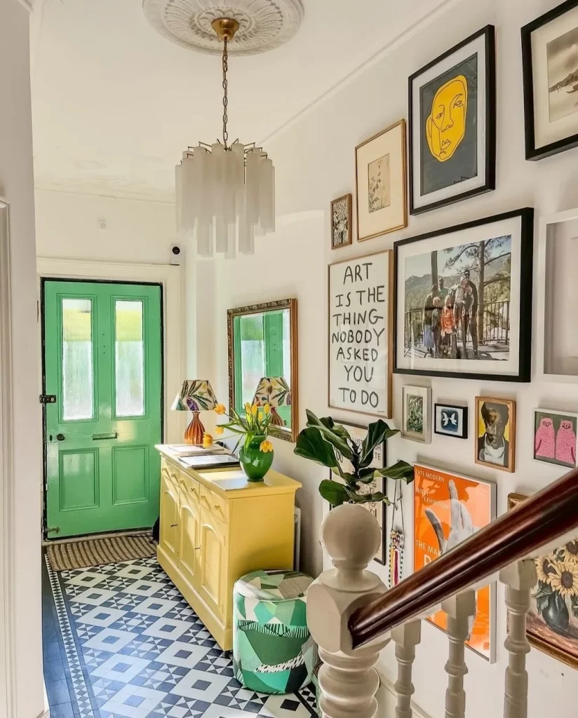 Galeria de quadros no hall de entrada com porta verde e móvel amarelo.