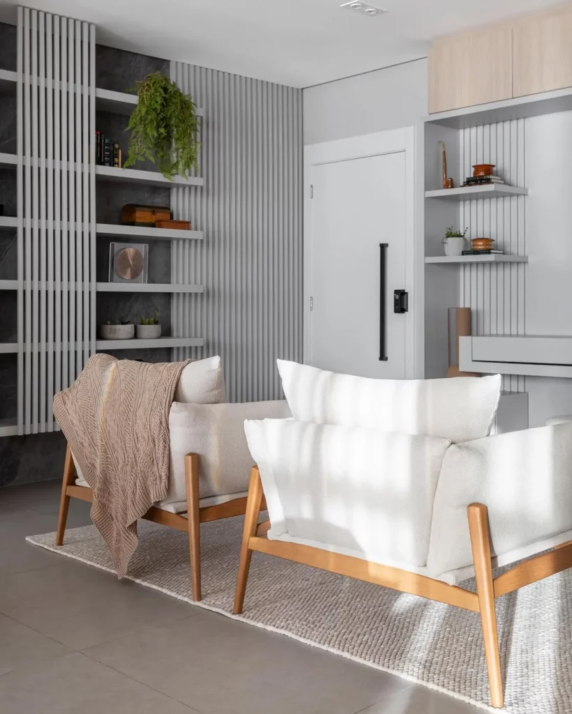 Hall compartilhado com a sala de estar com estantes na parede e poltronas.