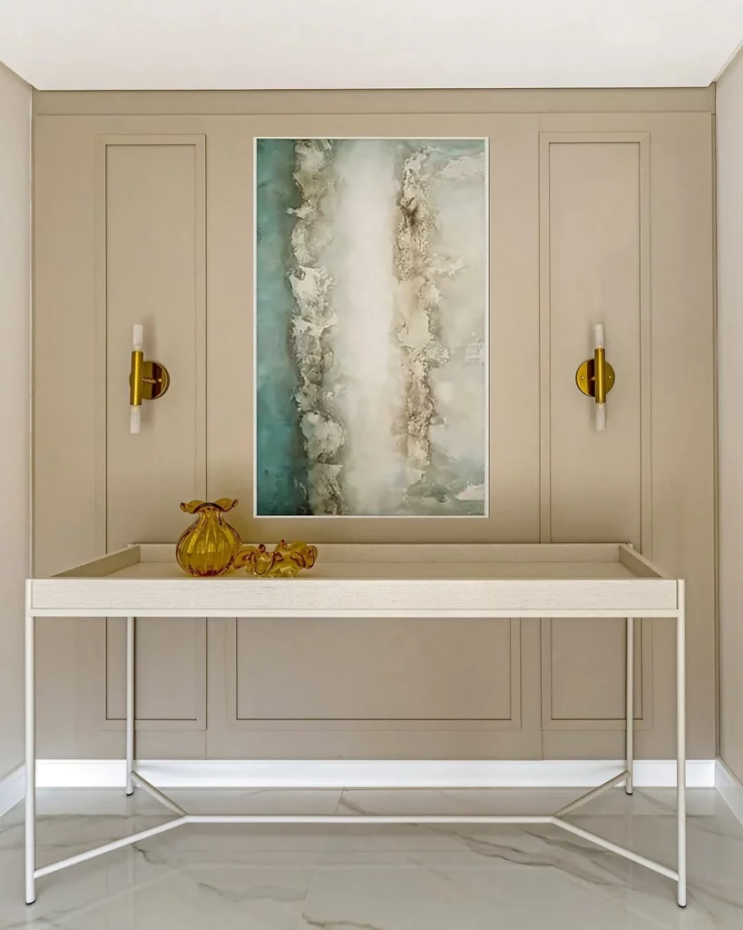 Hall de entrada espaçoso com um quadro na parede, arandelas e um aparador grande.