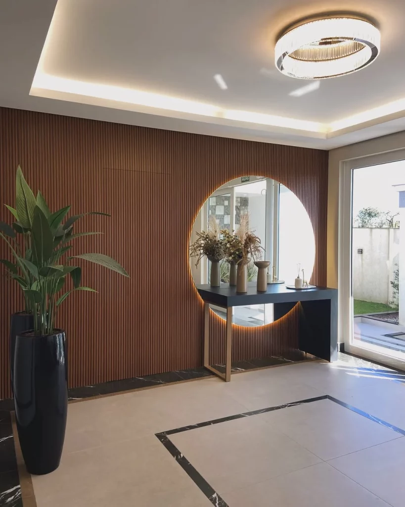 Hall de entrada com espelho redondo e vaso preto na parede oposta.