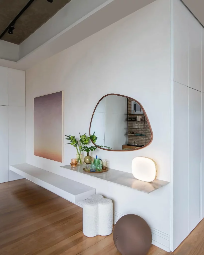 Hall de entrada extenso com prateleira suspensa, banco, espelho e quadro na parede.