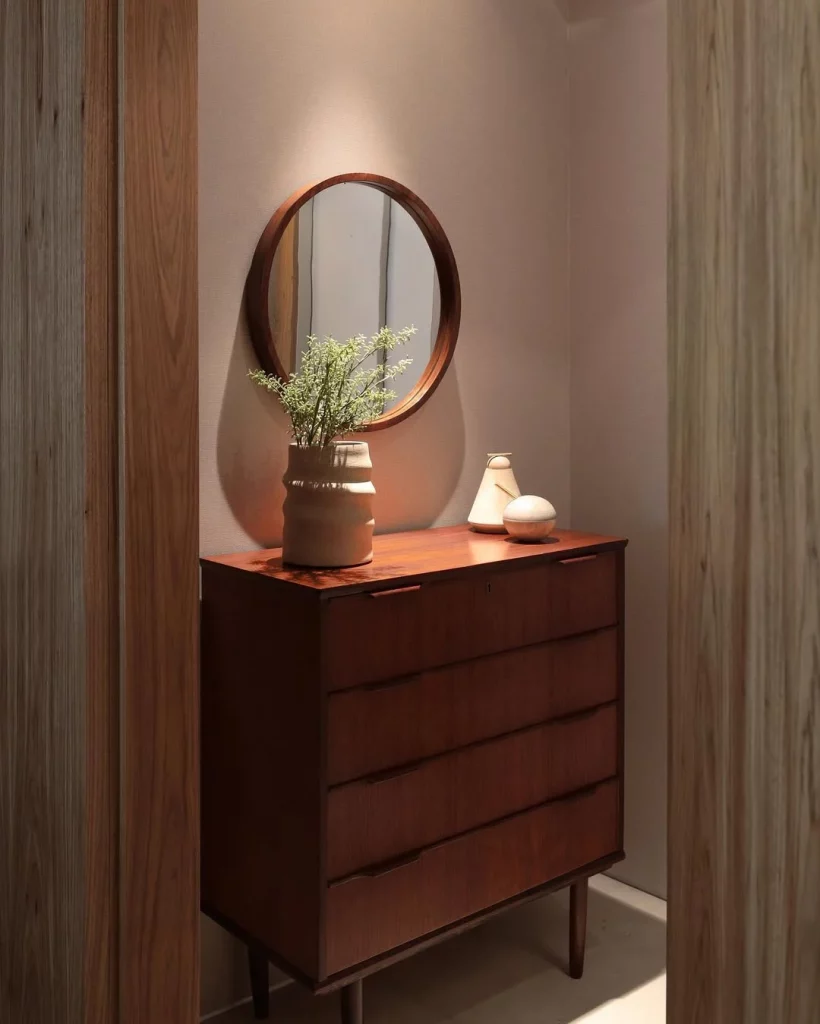 Hall de entrada com espelho e cômoda de madeira.