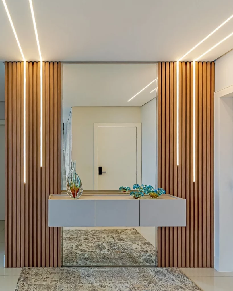 Decoração de hall de entrada com espelho e painel ripado.