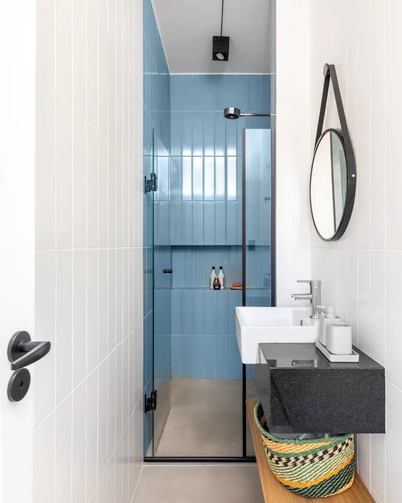 Nicho embutido na cor azul no box do banheiro pequeno.