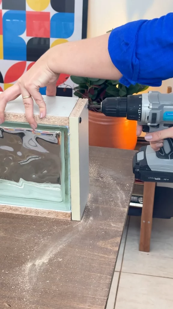 Parafusando as ripas de madeira feitas com porta de guarda-roupas nos blocos de vidro.