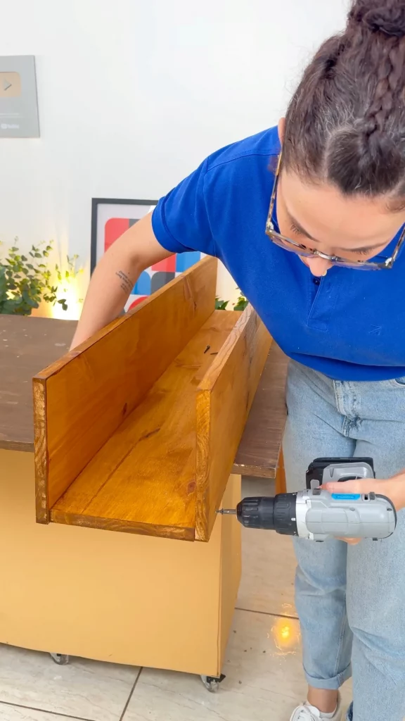 Parafusando as três tábuas menores de maedira para fazer a base da divisória de ambientes.