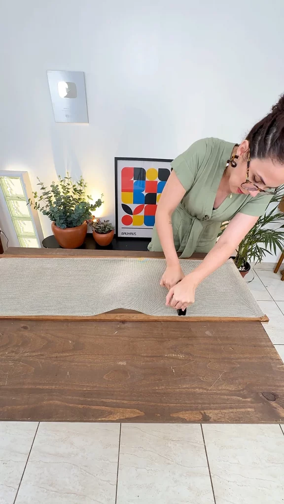 Grampeando a talagarça na moldura de madeira da divisória de ambientes.