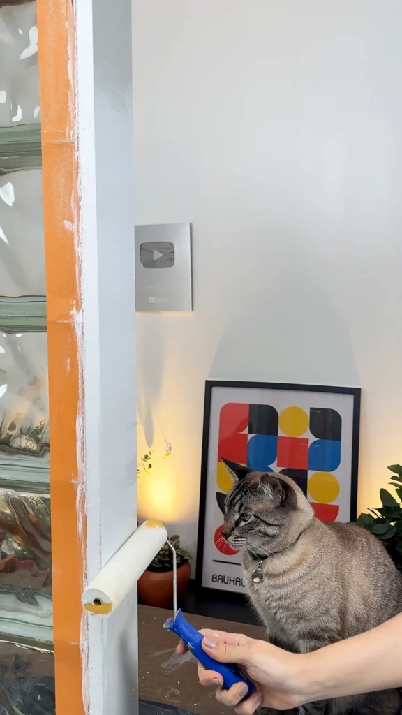 Pintando a luminária com rolo de tinta na cor branca.