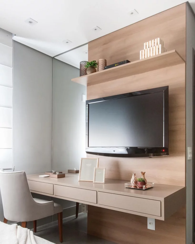 Penteadeira com espelho grande ao lado do painel da tv.